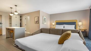 Une chambre d’hôtel avec un grand lit, un bureau et une chaise. Deux tableaux encadrés sont accrochés au mur.