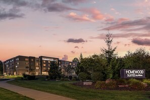 A hotel with a sign reading 'Homewood Suites by Hilton' and a well-maintained lawn in front.