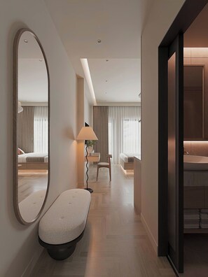Une chambre d’hôtel moderne, dotée d’un grand miroir, d’un banc, d’un bureau et d’un canapé.