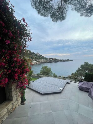 Eine Terrasse mit Meerblick, eine Mauer aus Stein mit Blumen und ein Fliesenboden.