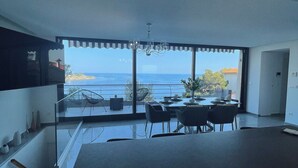 A modern interior with a large dining area, a staircase, and a view of the sea. - Luxe 3-bedroom apartment on sea front in Cap-d'Ail with AC / Private pool (Cap-d'Ail)