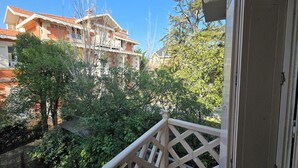 Un balcon donnant sur un immeuble et des arbres.