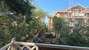 Une vue d’un immeuble doté d’un balcon, entouré d’arbres et de verdure.