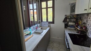 Une cuisine de taille réduite, dotée d’une fenêtre, d’un four à micro-ondes et d’un évier.
