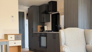 A modern kitchen with dark cabinetry, a built-in oven, and a gas stove. - Beautiful new chalet with private parking space on the edge of the park. (Sint Maarten)