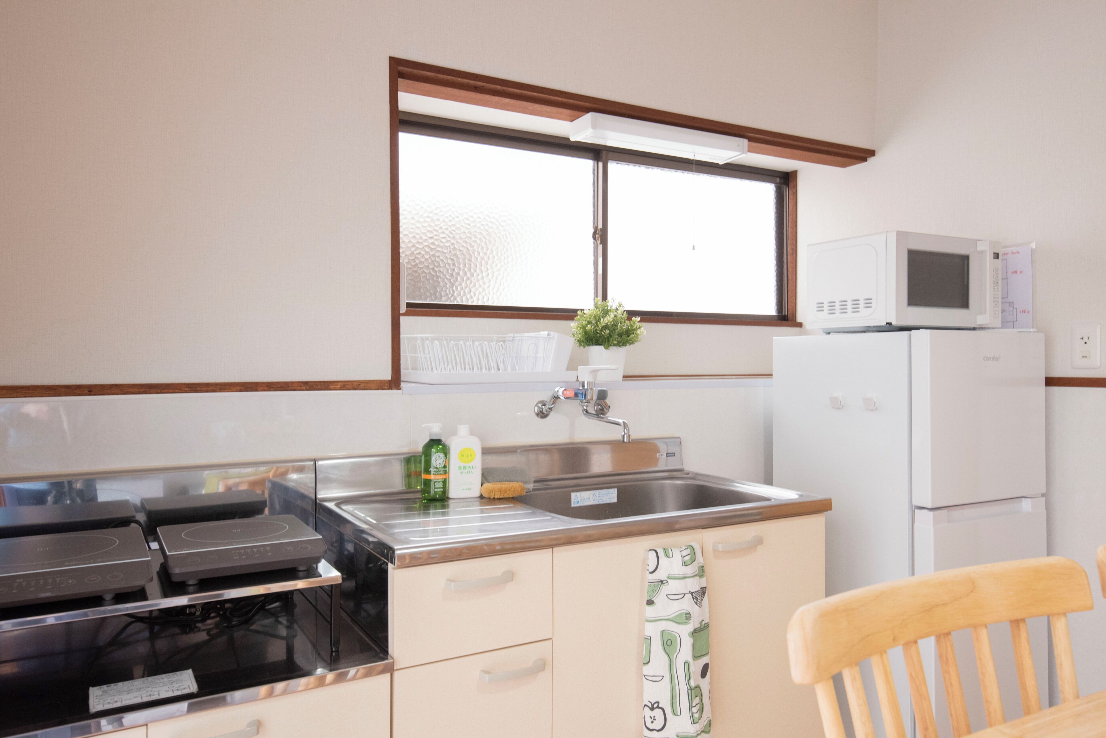 A kitchen with a stove, microwave, sink, and a window above the sink.