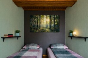 A room with two beds, a painting of a forest, and shelves with books and plants. - Apartment Waldeck - comfortable, spacious accommodation in natural surroundings (Twistetal)