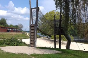 A playground with a climbing net, a wooden structure, and a sandy area. - Apartment Waldeck - comfortable, spacious accommodation in natural surroundings (Twistetal)