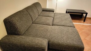 Um sofá modular numa sala com chão em mosaico e uma pequena mesa preta.