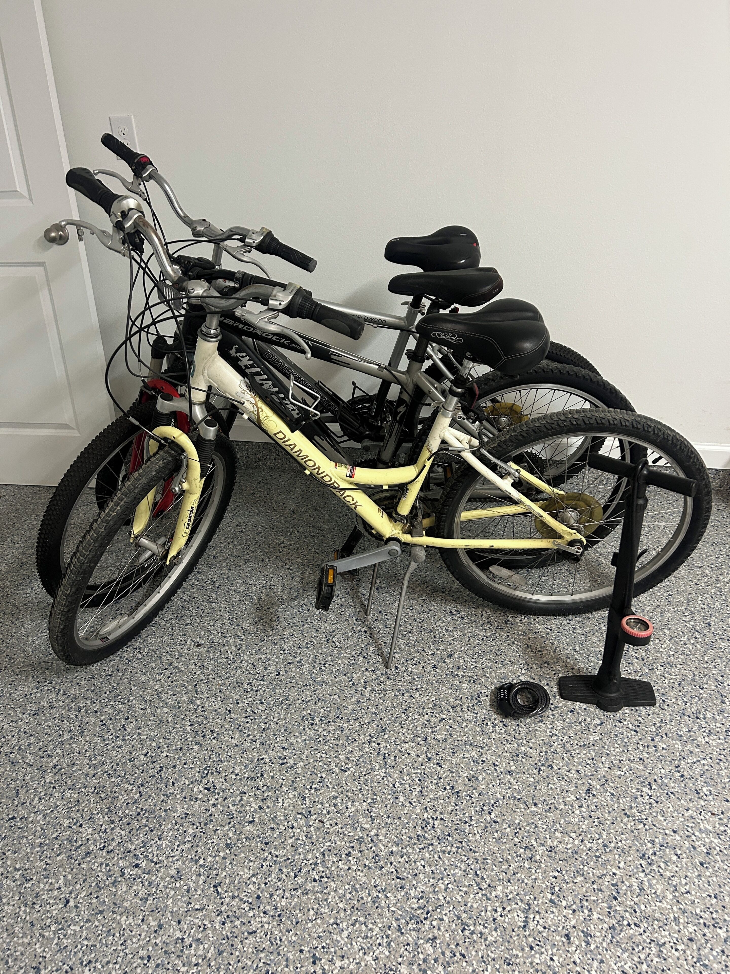 Una bicicleta con un cuadro amarillo y componentes negros, apoyada contra una pared.