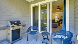 A covered patio with a grill, two chairs, and a sliding glass door leading to an interior living area. - Beach, Eats, Shops! Sunny Stay in our New 3BR Townhome in Peaceful Palm Coast FL (Palm Coast)