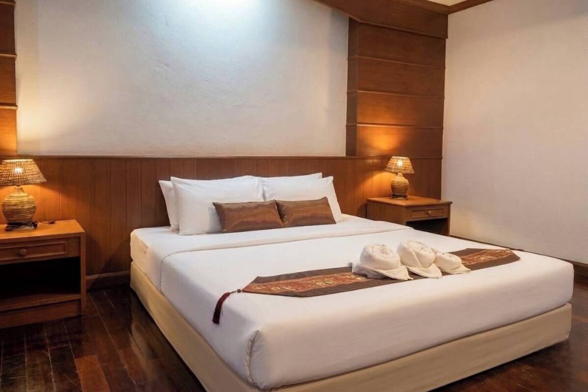 Una habitación de hotel con una cama grande, dos mesitas de noche y un cabecero.
