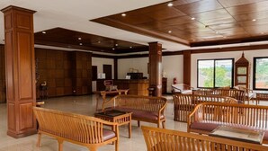 A spacious lobby with wooden furniture, a reception desk, and large windows. - Lanna Oriental Maejo (San Sai)