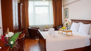 A hotel room with a bed, bedside table, chair, and a desk with a lamp. - Diwa Hotel (Tetovo)