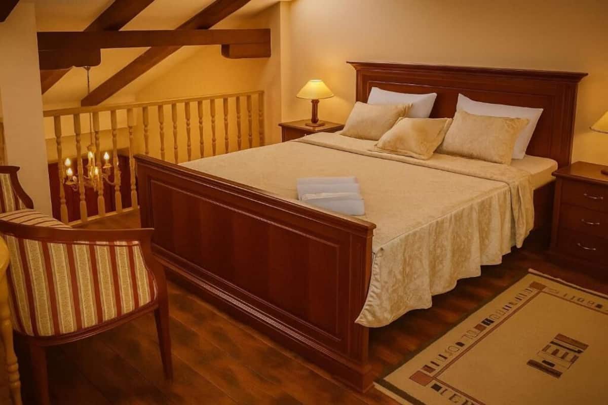 Un dormitorio con una cama de madera, mesitas de noche, una silla y una araña.