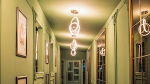 A hallway with patterned floor tiles, framed pictures on the walls, and ornate mirrors. - Diwa Hotel (Tetovo)