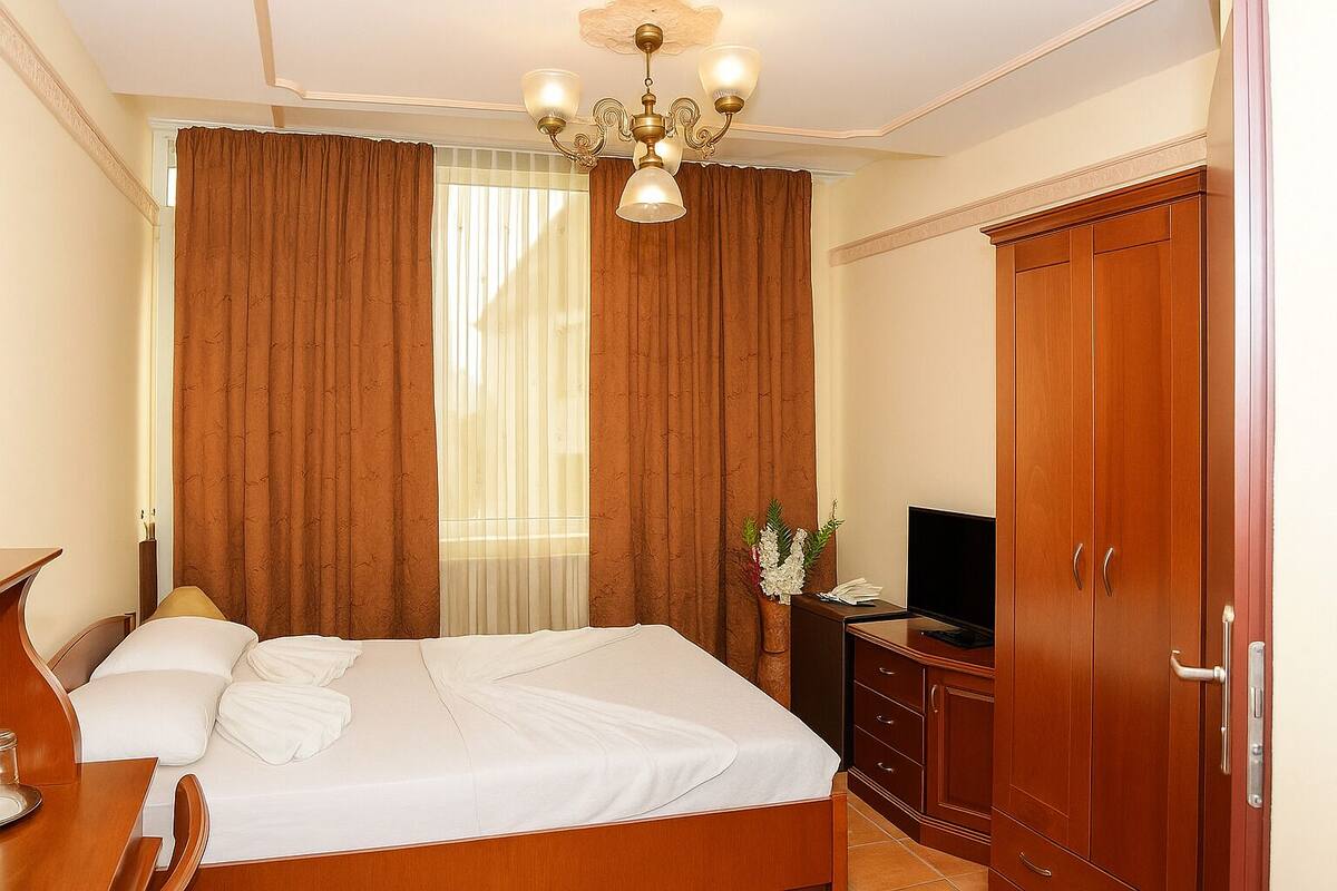 Una habitación de hotel con cama, televisión, escritorio y armario.