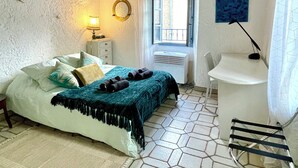 A bedroom with a bed, a bedside table, a lamp, a window, a chair, and a towel rack. - Cosy, charming townhouse in Valbonne Village (old town) (Valbonne)