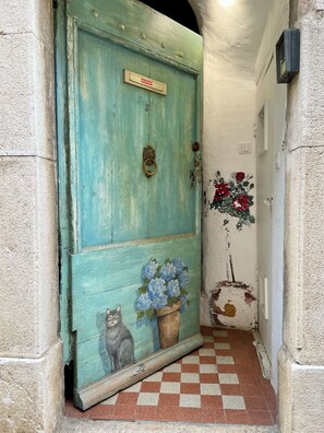 A teal door with a cat and flowers painted on it, a checkered floor, and a wall with peeling paint. - Cosy, charming townhouse in Valbonne Village (old town) (Valbonne)