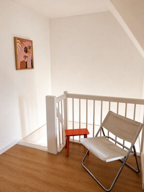 Ein Zimmer mit weißer Reling, einer roten Bank und einem Canvas-Sessel.