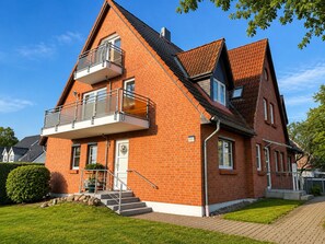 Ein zweistöckiges Haus mit Balkon, Eingangstür und kleinem Vorgarten.
