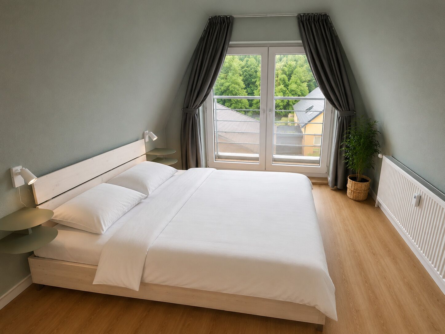 A bedroom with a bed, a bedside table, a lamp, a window with curtains, a potted plant, and a radiator.