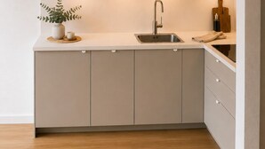 A modern kitchen with a built-in oven, a stainless steel sink, and a wooden cutting board.