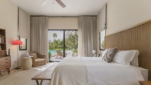 Una camera da letto con un letto, una scrivania, una sedia, una libreria e vista su una piscina.