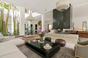 Ein modernes Wohnzimmer mit Sofa, Couchtisch und einer großen Hängelampe.