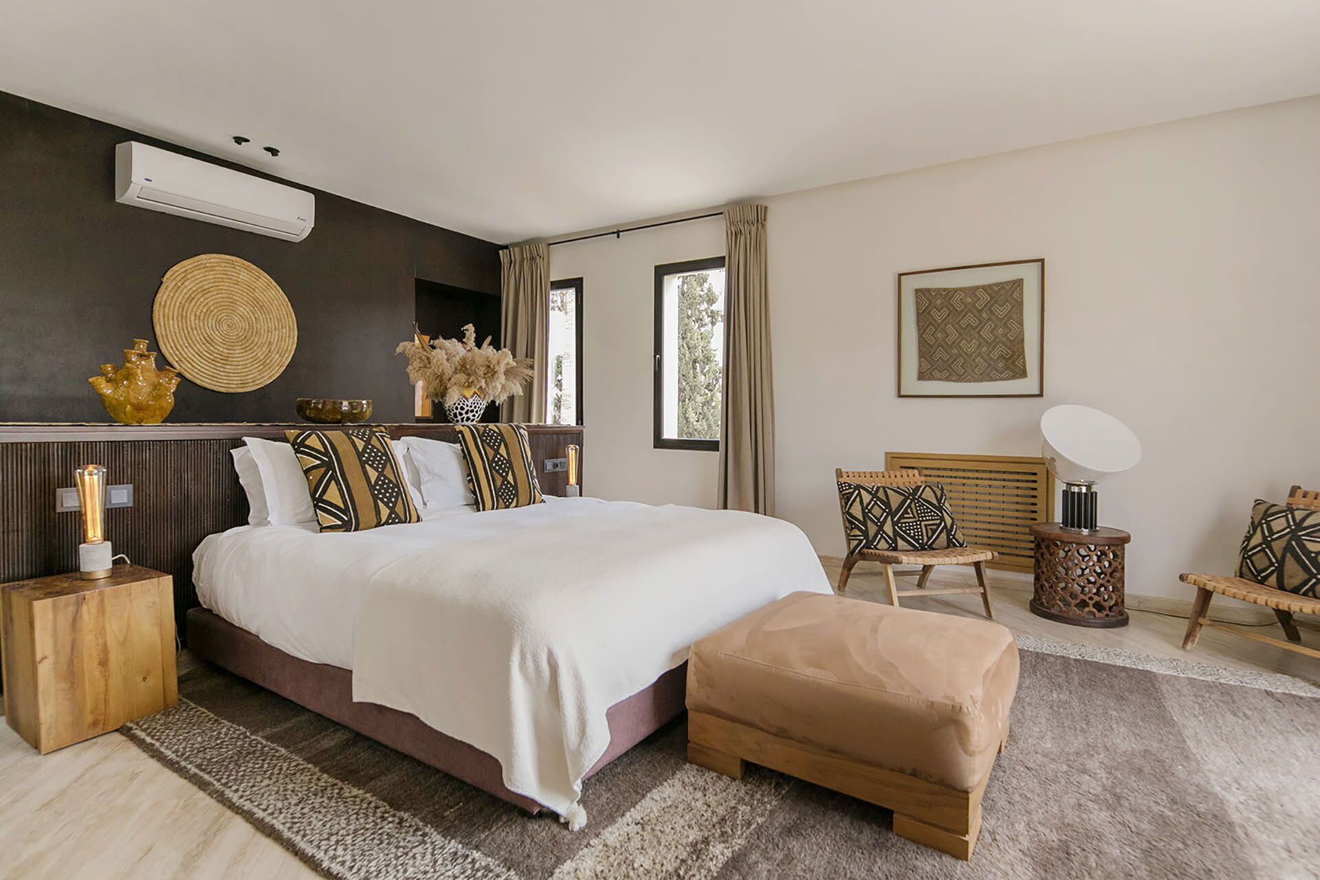 Une chambre moderne avec un grand lit, des tables de chevet, une chaise, une table d’appoint et une fenêtre.