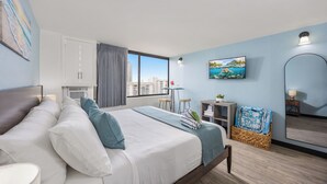 Une chambre d’hôtel moderne dotée d’un grand lit, d’un bureau, d’une chaise, d’une télévision et offrant une vue sur la ville.