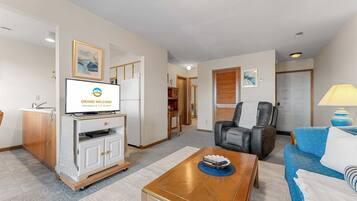Ein Hotelzimmer mit Fernseher, einer Couch, einem Sessel, einem Couchtisch und einer Lampe.