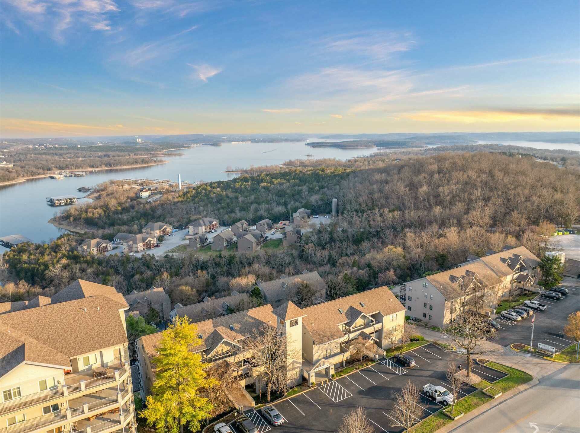 A residential area with houses, a parking lot, and a body of water in the background.