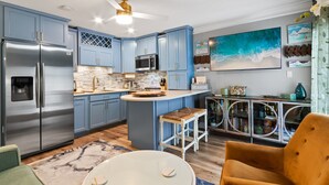 Une cuisine moderne avec des meubles bleus, des appareils en acier inoxydable et un îlot central.