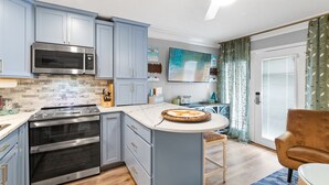 Une cuisine moderne dotée d’un îlot central, d’un four encastré, d’un four à micro-ondes et d’appareils électroménagers en acier inoxydable.