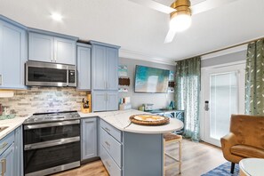 Een moderne keuken met een centraal eiland, inbouwoven, magnetron en roestvrijstalen apparatuur.