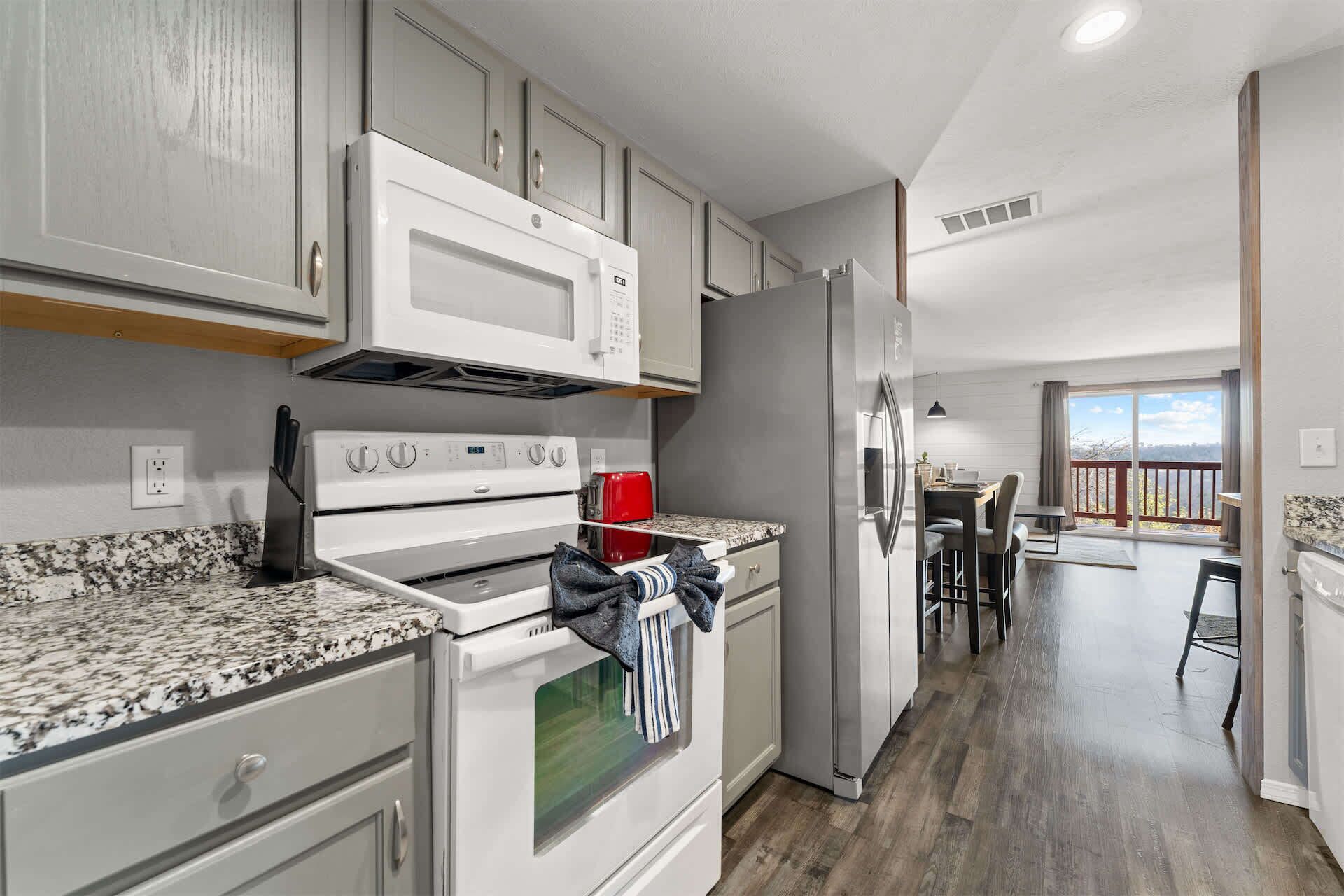 A modern kitchen with granite countertops, stainless steel appliances, and a dining area with a view.