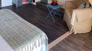 A room with a bed, a small blue table with a plant, a wooden staircase, and a door. - Bedroom and bathroom (Gragnague)