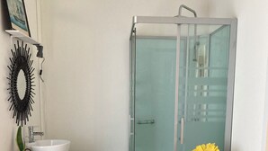 A bathroom with a glass-enclosed shower, a sink, a mirror, and a framed picture on the wall. - Bedroom and bathroom (Gragnague)