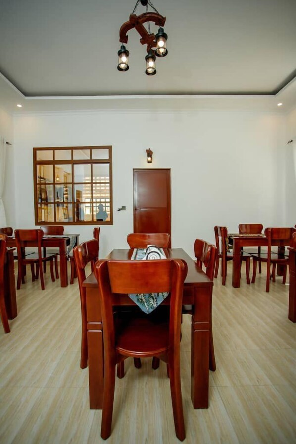 A dining area with wooden furniture, a large mirror, and a ceiling light fixture. - Paki Hotels & Apartments (Moshi)