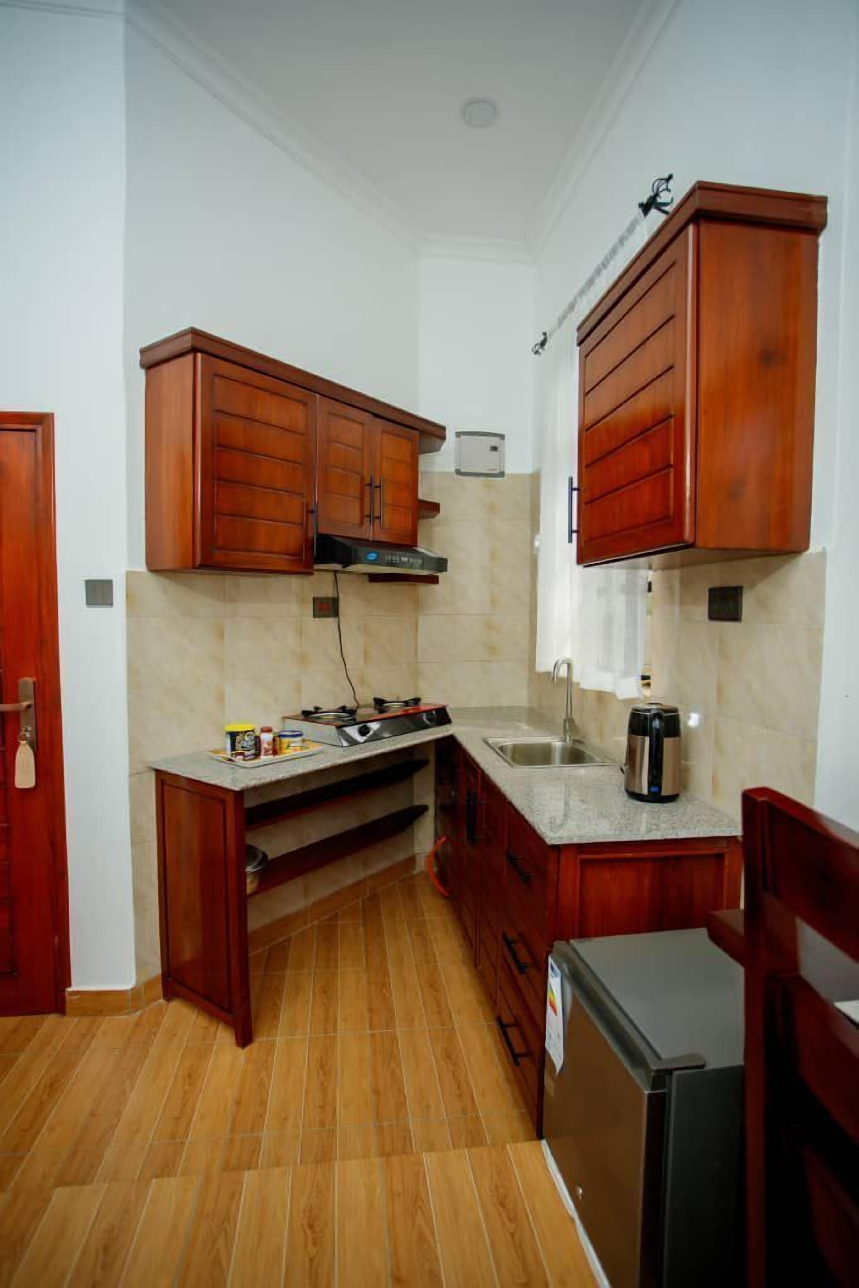 A compact kitchen with wooden cabinets, a built-in stove, a sink, and a refrigerator.