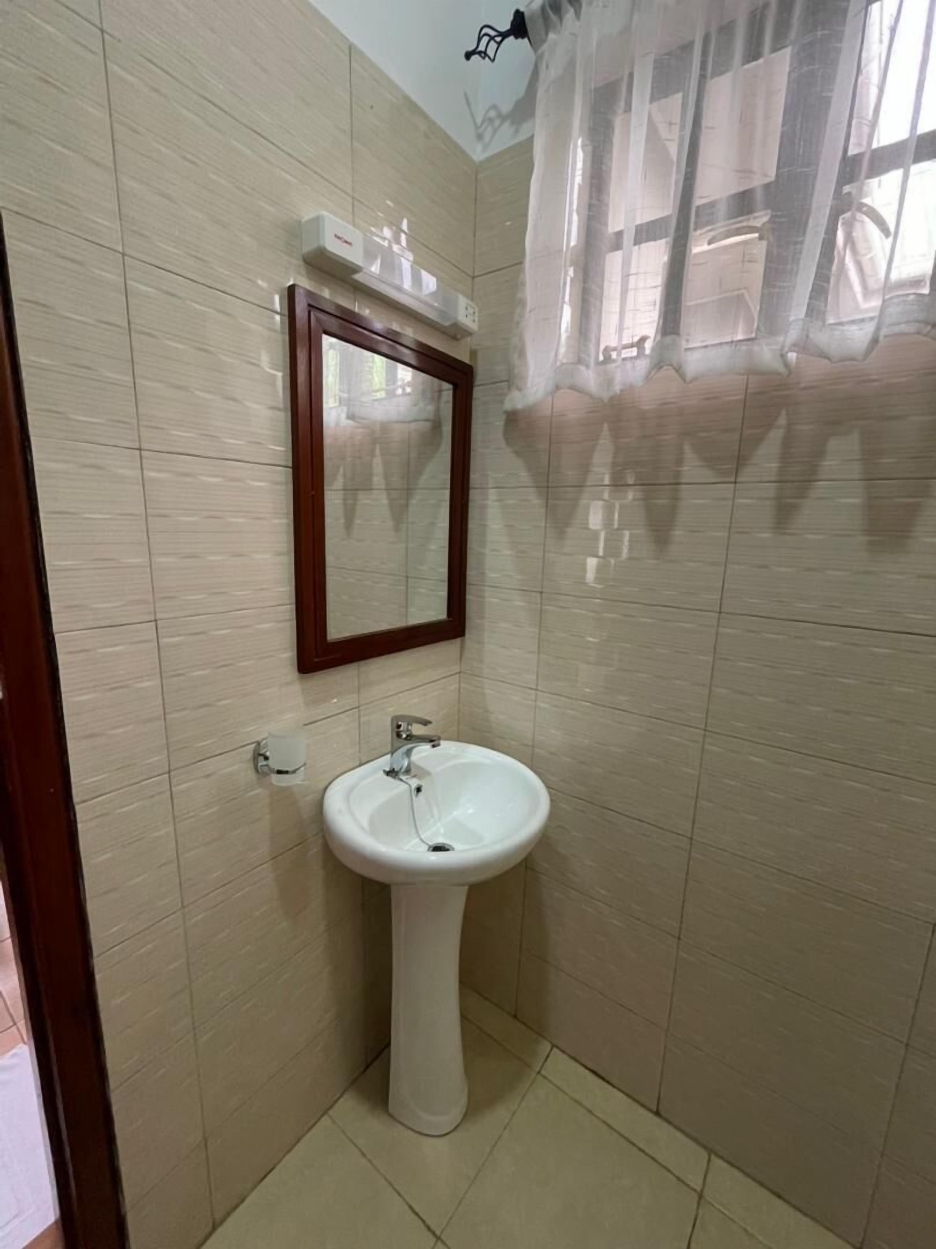 A bathroom with a pedestal sink, a mirror, and a shower curtain.