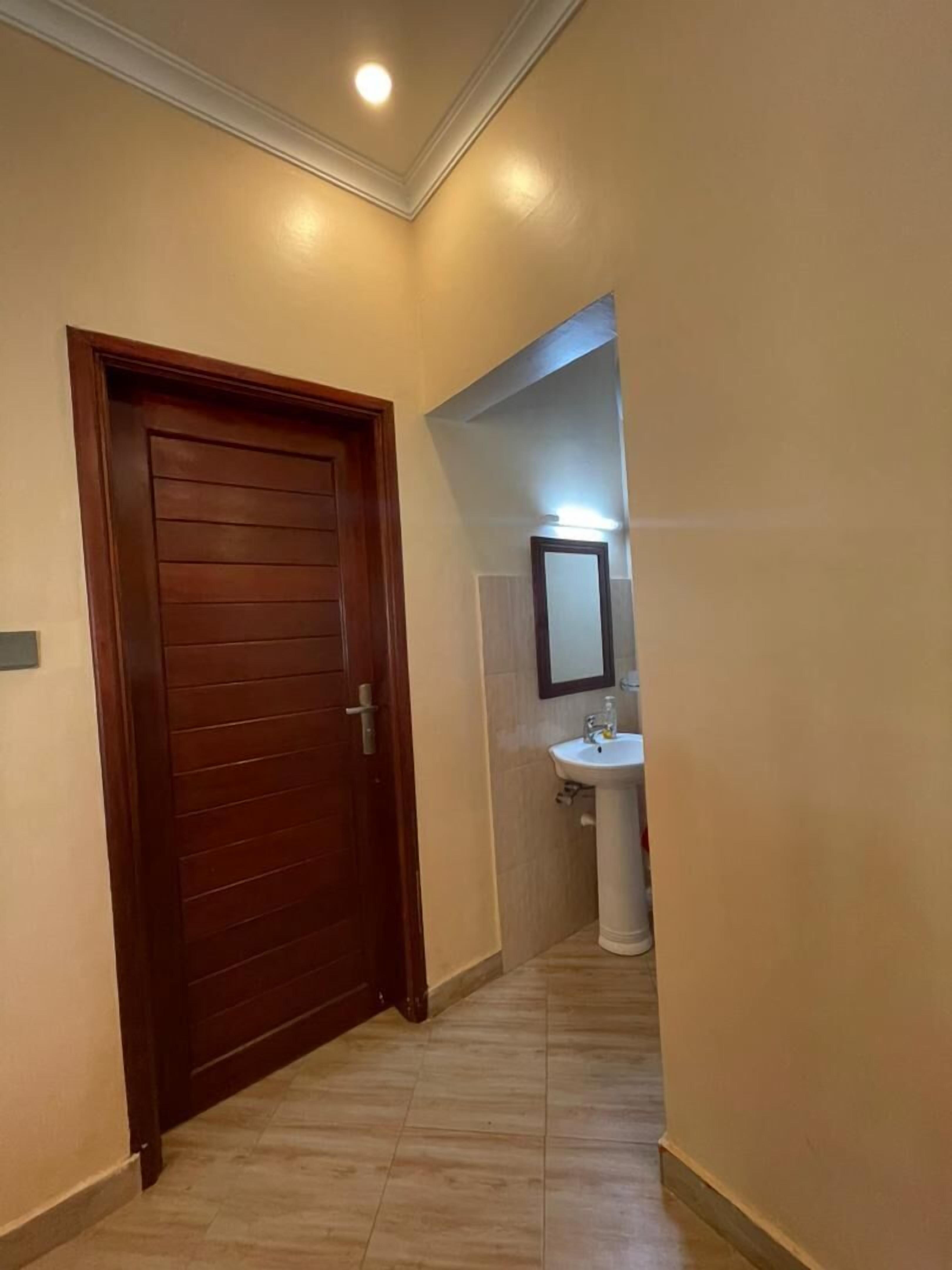 Un pasillo con una puerta de madera, un lavamanos blanco y un espejo.