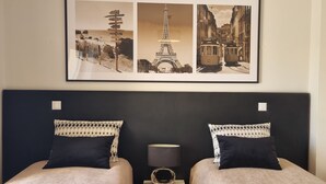Een hotelkamer met een bed, twee kussens, een nachtkastje, een lamp en een ingelijst foto boven het bed.