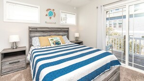 A bedroom with a bed, two nightstands, a ceiling fan, and a view of the outside. - Topsail Fairytale - with sweeping ocean views from three front decks! (Surf City)