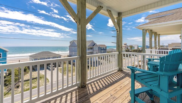 A covered porch with a view of the beach, wooden deck, and blue chairs. - Topsail Fairytale - with sweeping ocean views from three front decks! (Surf City)