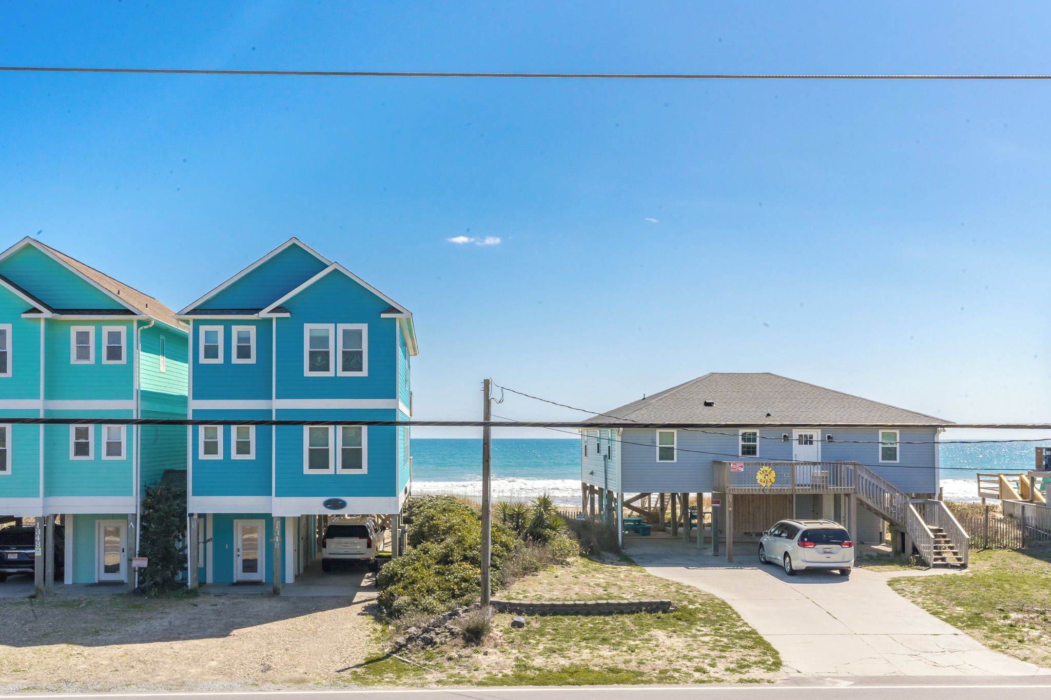 A coastal property with a two-story house, a single-story structure, and a beach view.