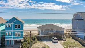 A beachfront property with a two-story house, a single-story house, and a parked car. - Topsail Fairytale - with sweeping ocean views from three front decks! (Surf City)