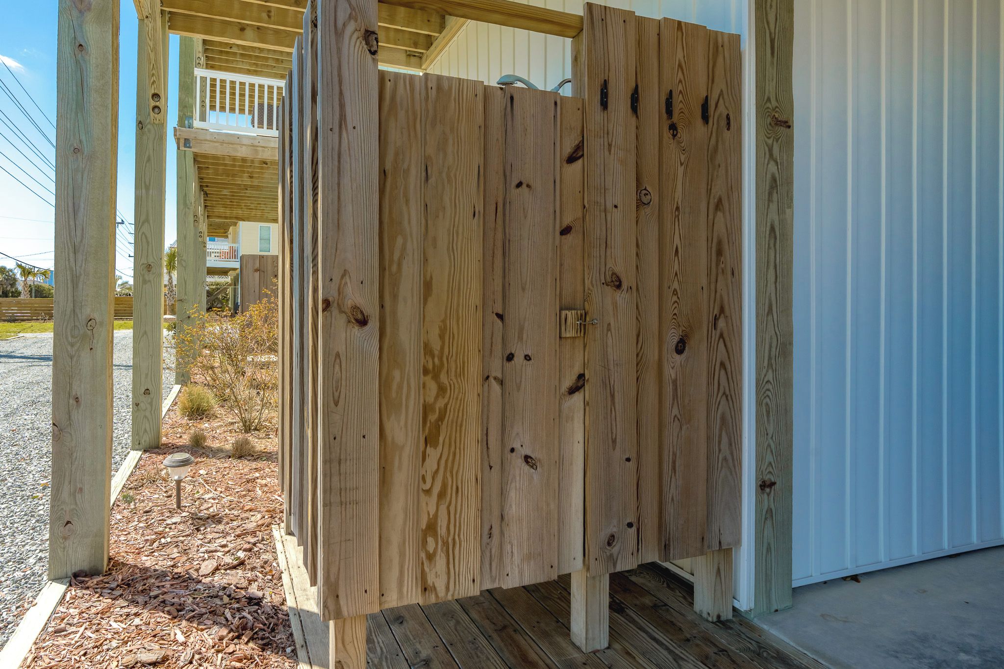A wooden gate leading to a covered porch area with a metal railing.