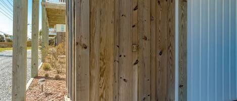 A wooden gate leading to a covered porch area with a metal railing.